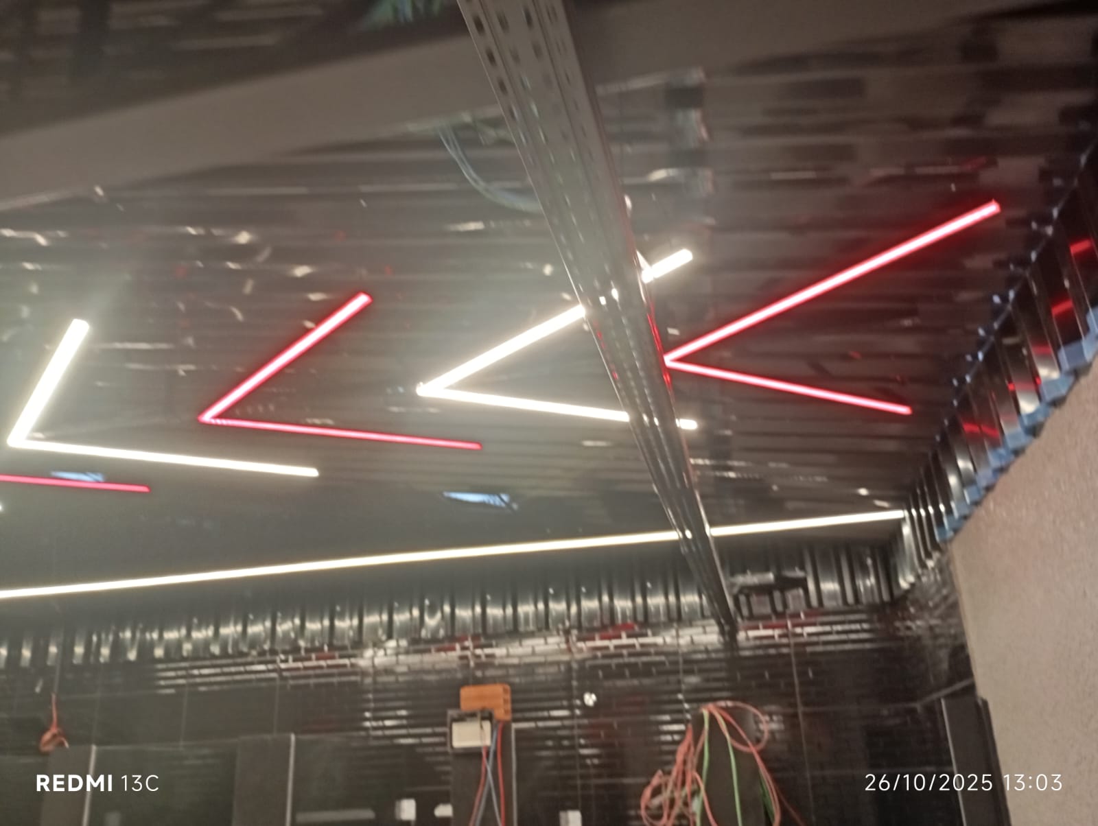 Iluminação LED geométrica em teto de ambiente comercial com eletrodutos aparentes